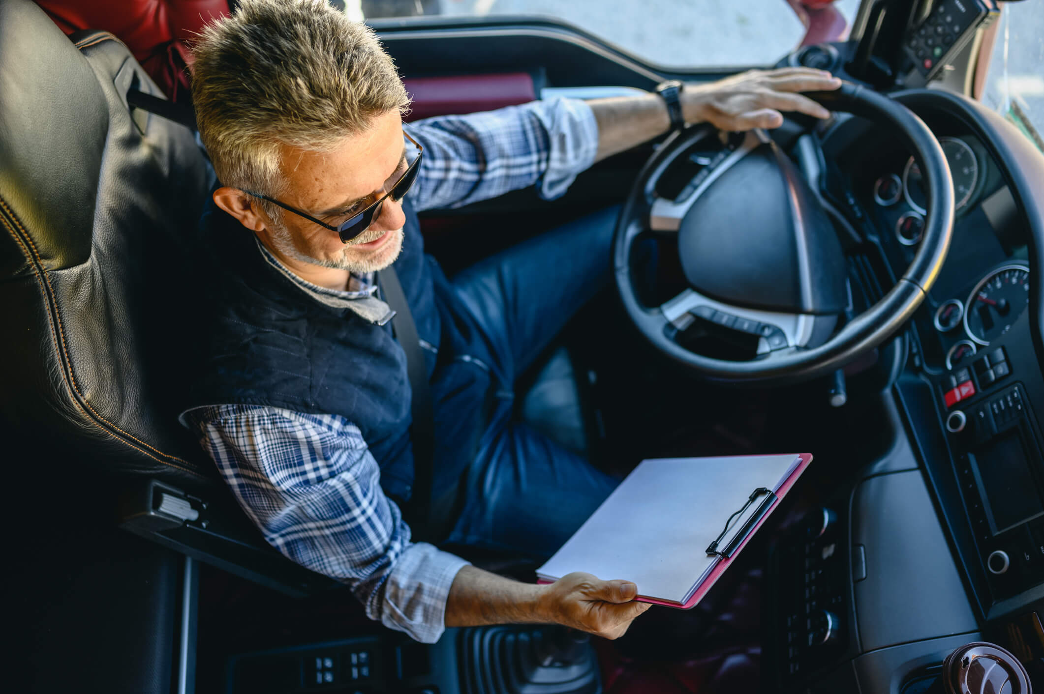 Man driving truck holding clipboard