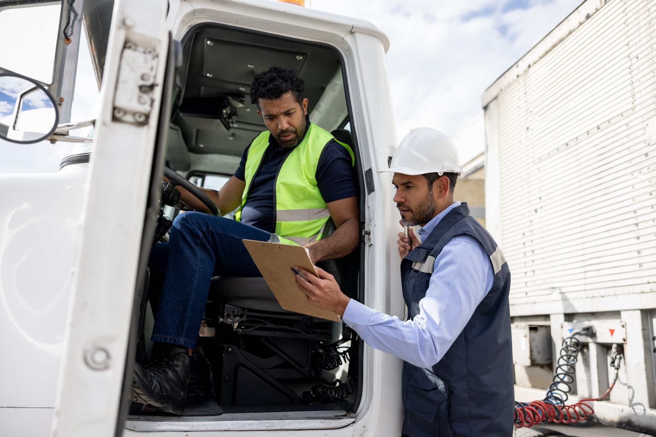 Foreperson talking to a truck driver while working at a distribution warehouse transporting merchandise - freight transportation concepts