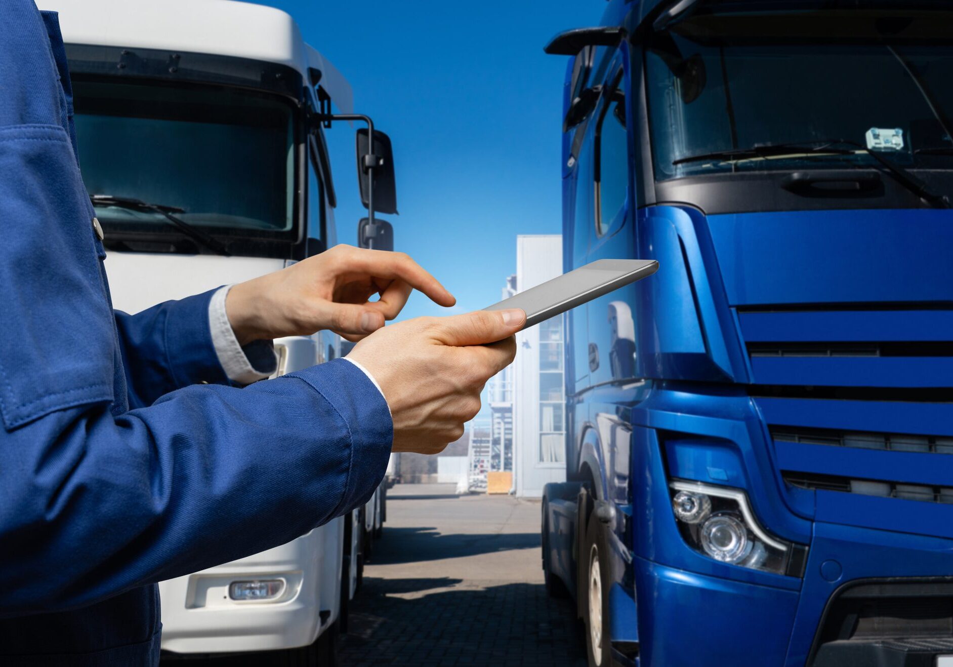 Fleet manager with digital tablet on a background of trucks.